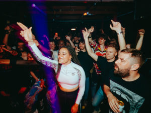 A group of clubbers with their hands in the air enjoying the music at The Venue at The Island.