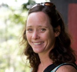 Profile shot of a white woman with long dark hair smiling at the camera